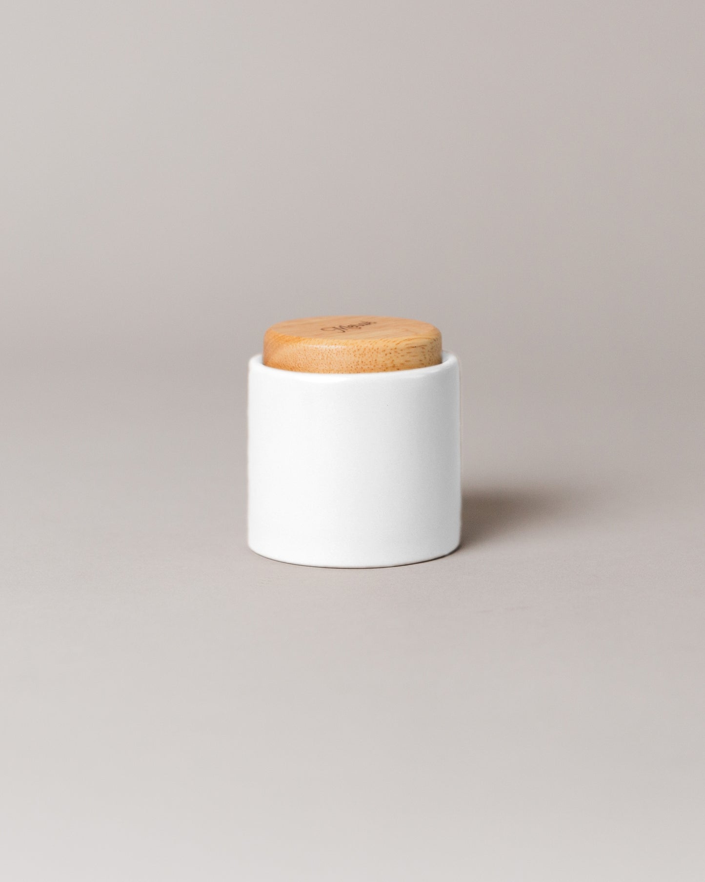 Upscale, ceramic, glacier white coffee cup with multiple key features. Built-in coaster, double wall, minimal handle for support, and spherical bottom for pouring. Made with high-quality ceramic and natural wood.